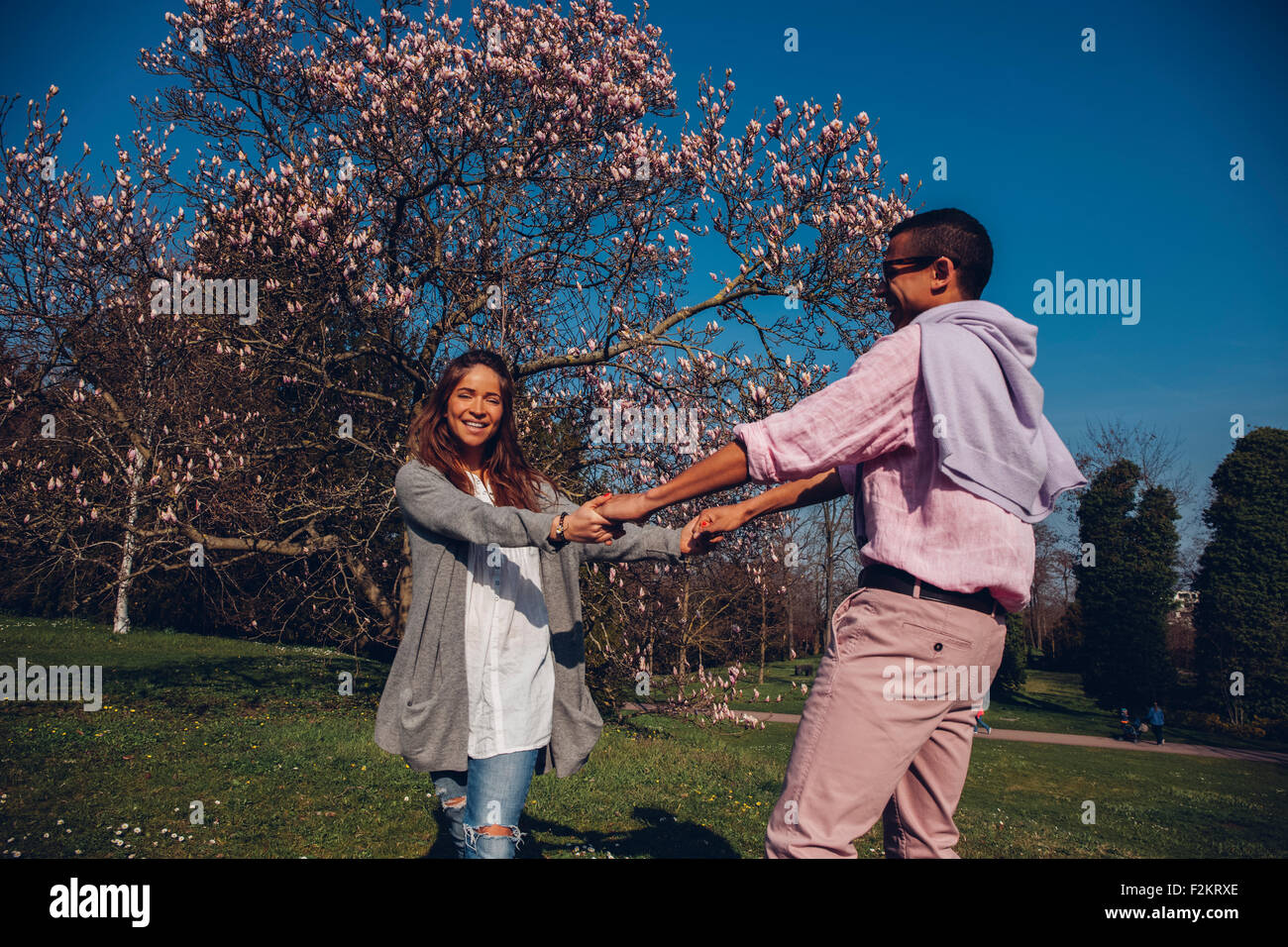Happy young couple holding hands in park Stock Photo - Alamy