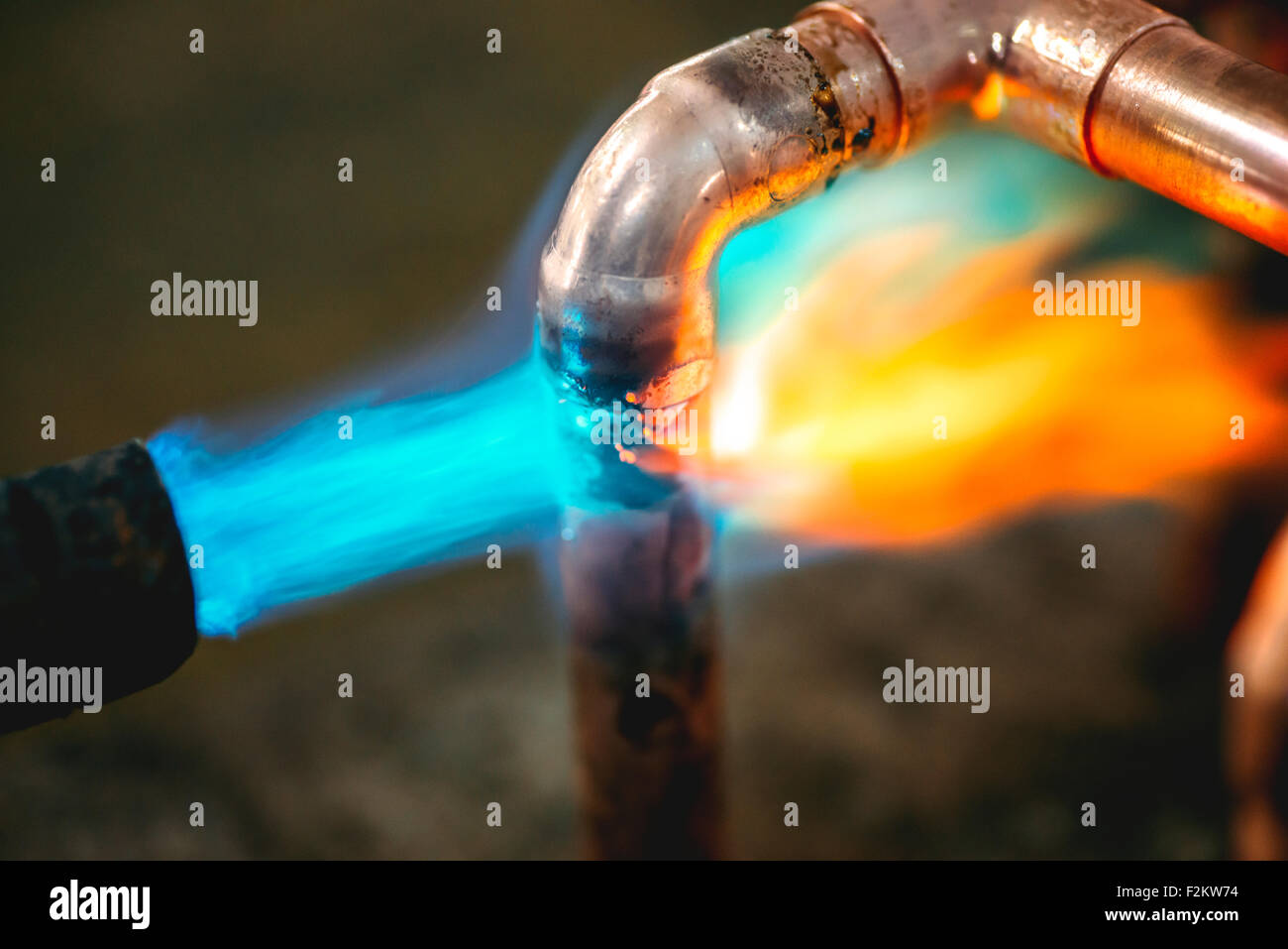A plumbers hot gas soldering burner heating a copper elbow fitting to