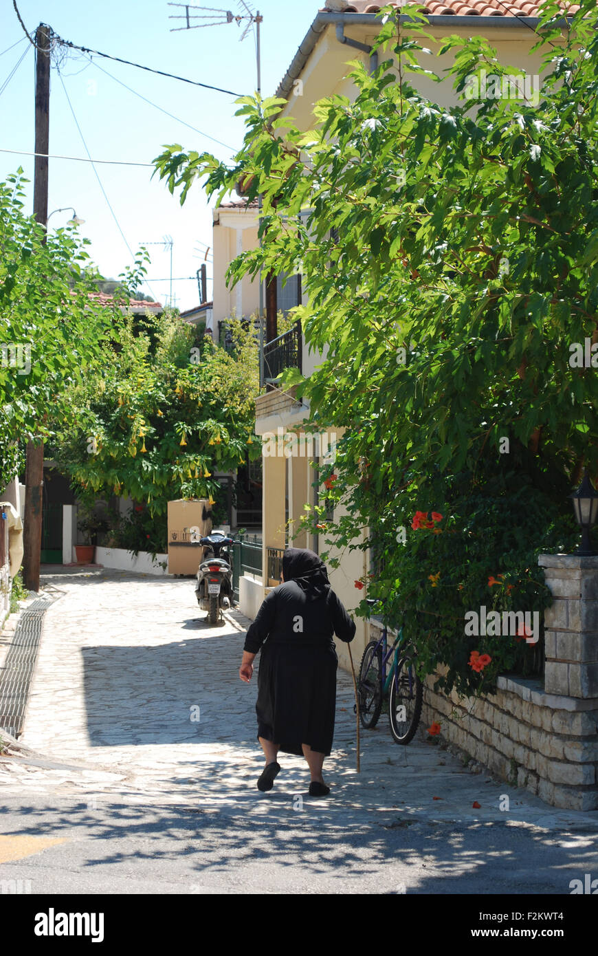 old Greek woman in traditional black clothing walking in Vathi Bay, Meganisi, Greece Stock Photo