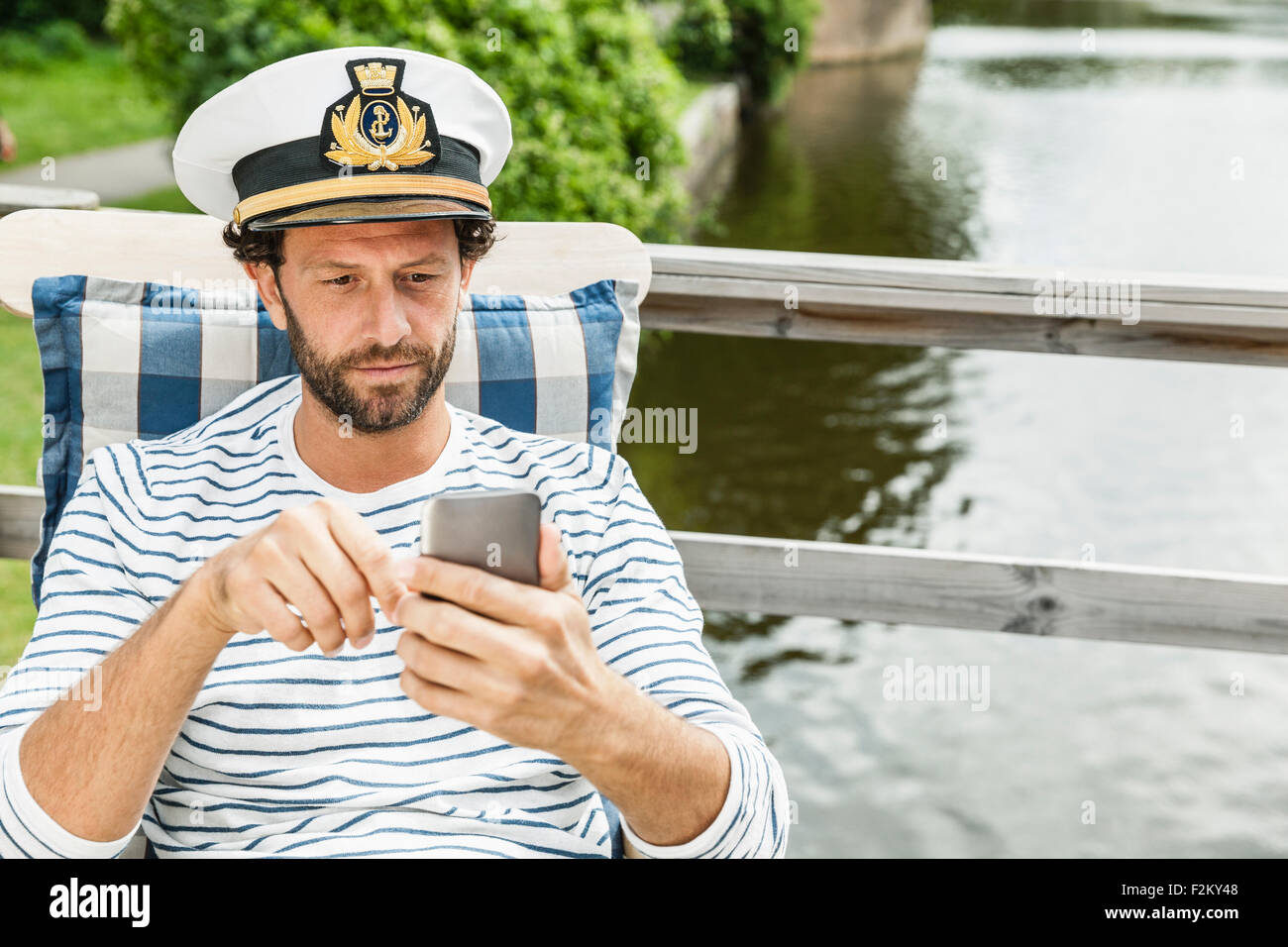 Man wearing captain's hat looking at cell phone Stock Photo Alamy