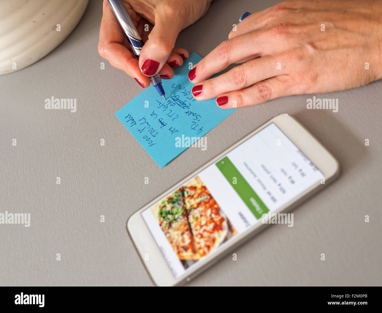Woman writing down recipe on a note Stock Photo