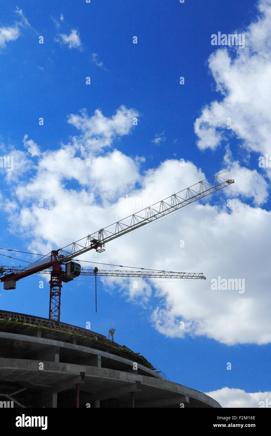 Cranes on construction site against blue sky and clouds. Stock Photo