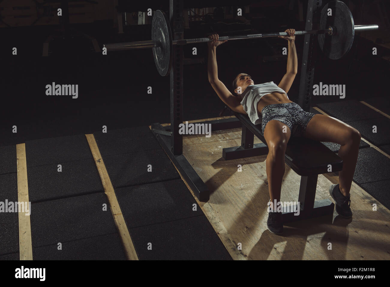 Female athlete doing bench presses with barbell Stock Photo