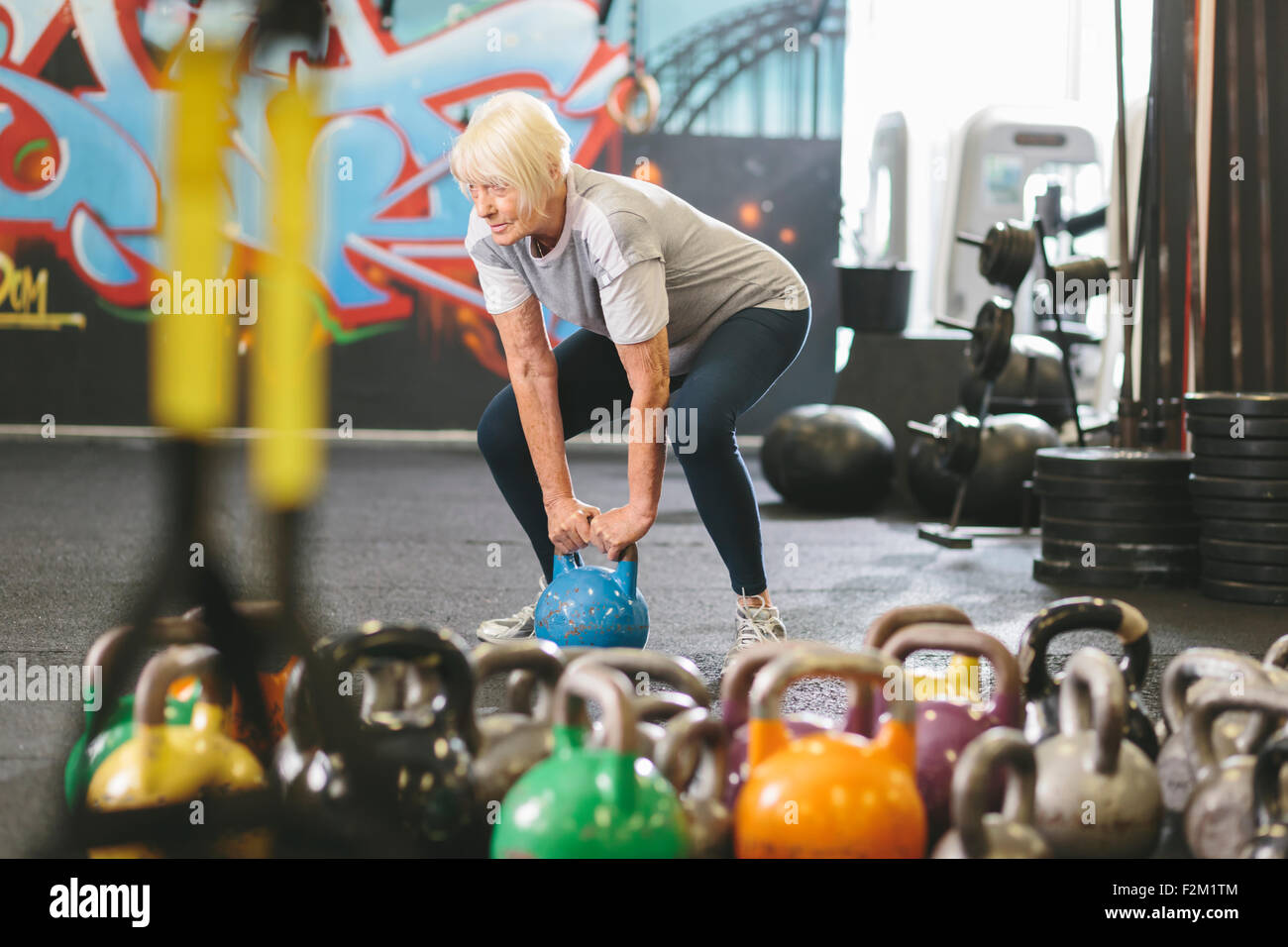 Senior woman in gym lifting kettlebell Stock Photo