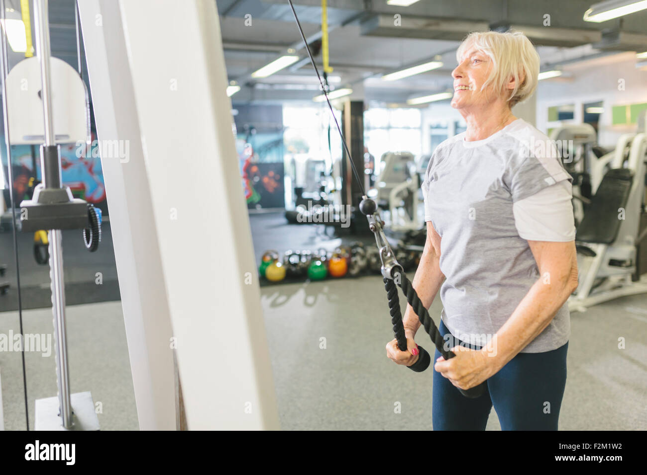 Smiling senior woman in gym exercising at cable machine Stock Photo - Alamy