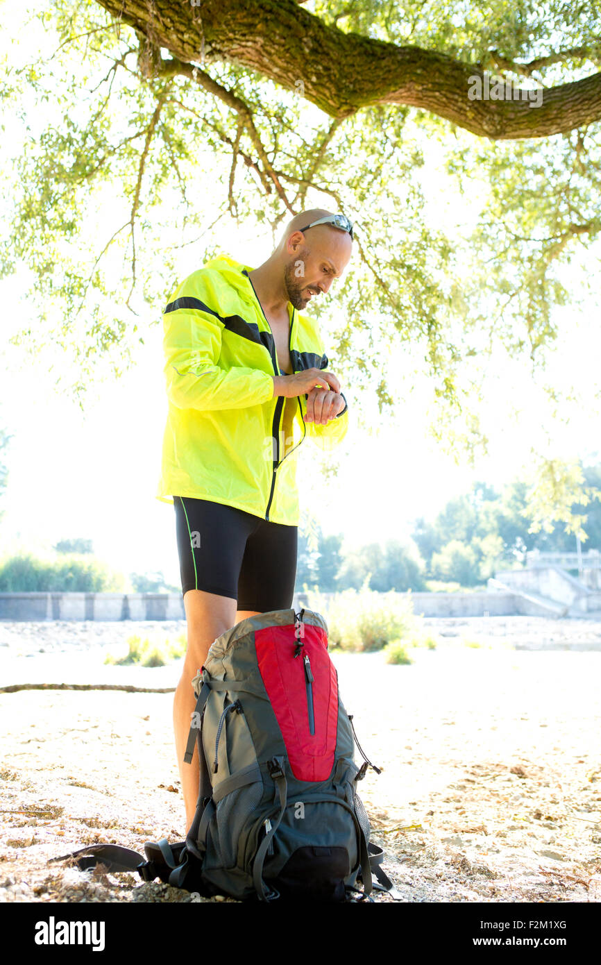 Man in sports wear with back pack adjusting his smartwatch Stock Photo
