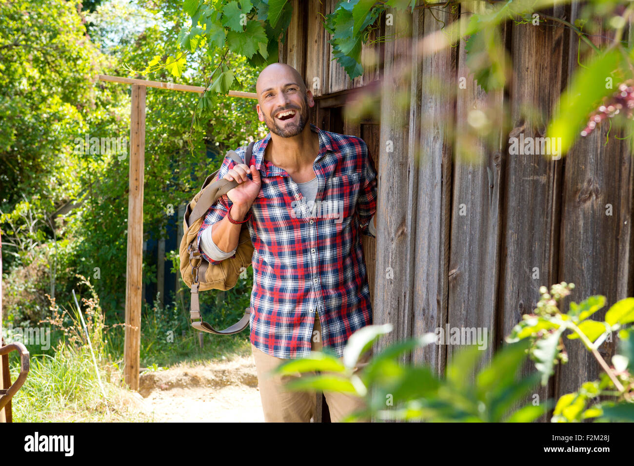 Smiling man standing at entrance door of wooden hut Stock Photo