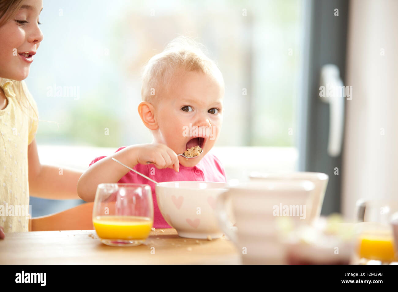 Baby girl eating muesli at breakfast table Stock Photo Alamy