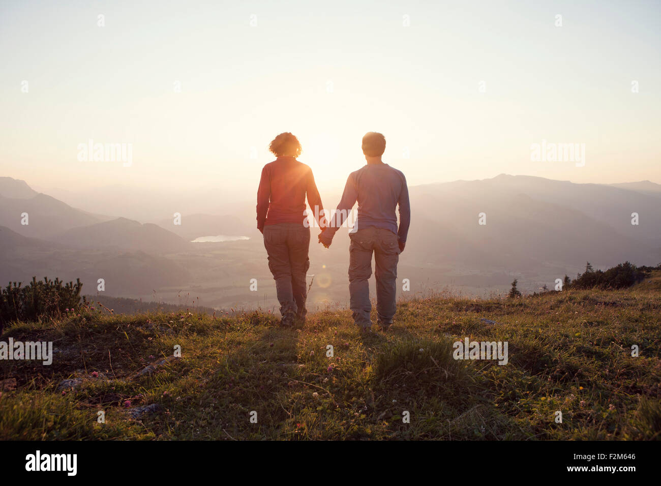 Austria, Tyrol, couple walking hand in hand at Unterberghorn at sunset Stock Photo