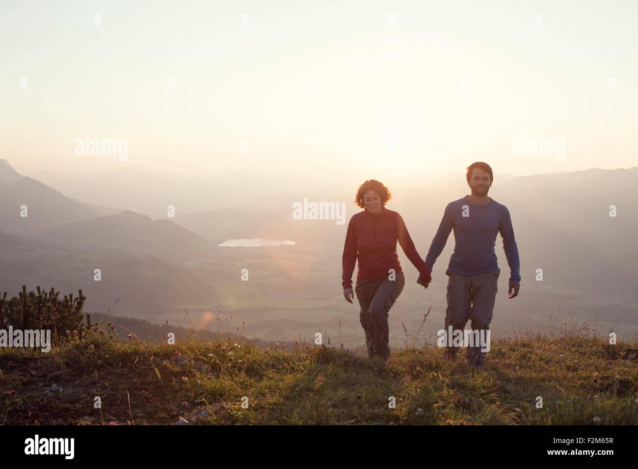 Austria, Tyrol, couple walking hand in hand at Unterberghorn at sunset Stock Photo
