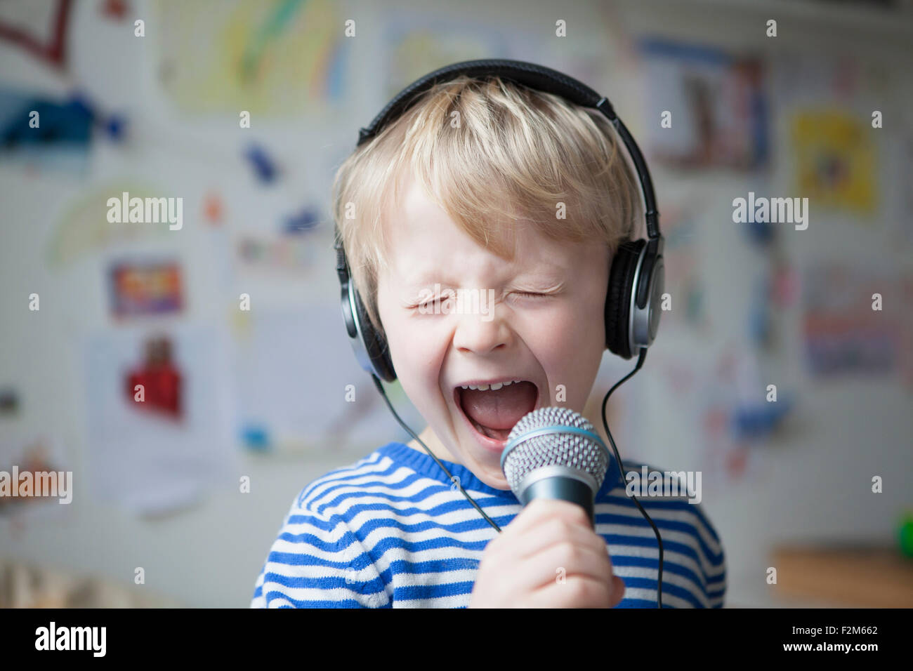 Portrait of singing little boy with headphones and microphone Stock Photo