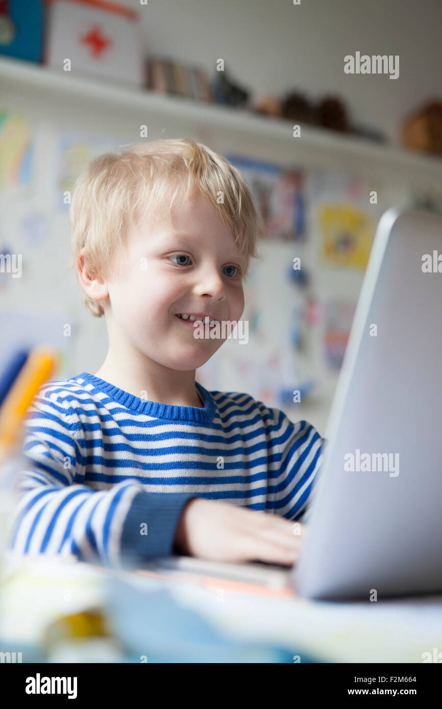 Portrait of smiling little boy using laptop Stock Photo - Alamy