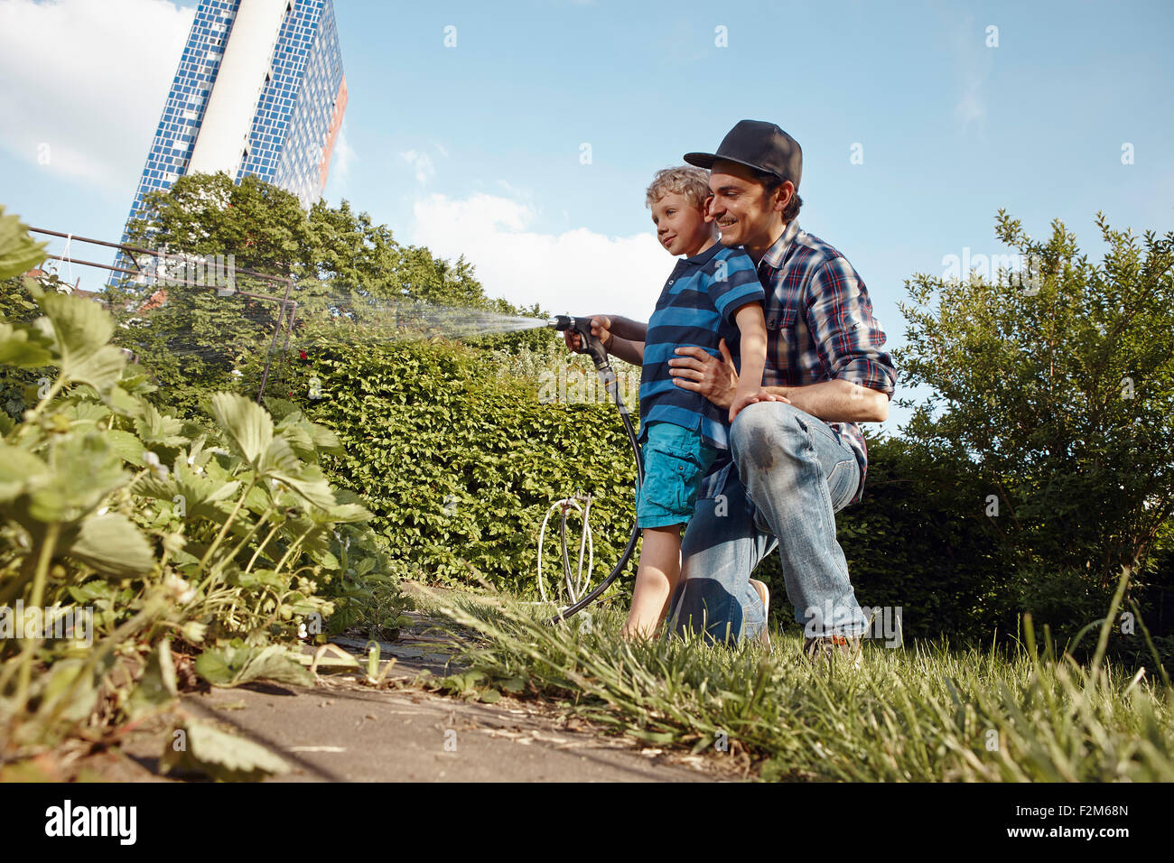Father and son watering plants in garden Stock Photo - Alamy