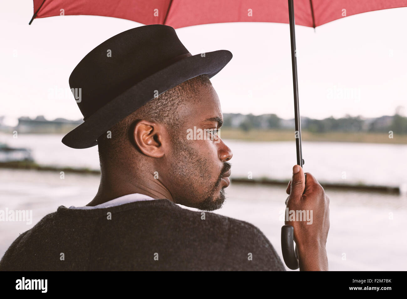 Young man holding umbrella Stock Photo - Alamy
