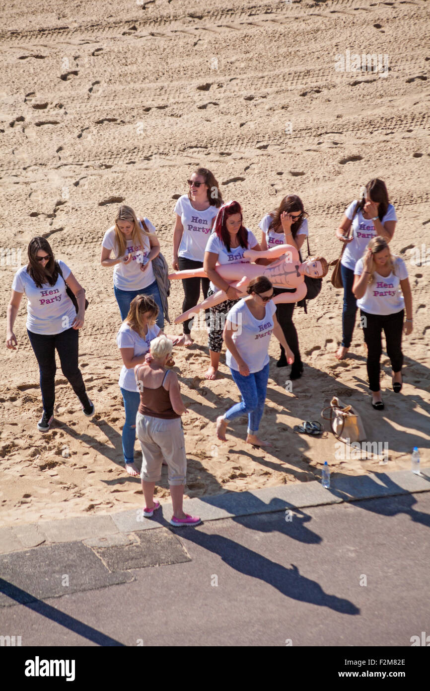 Hen party with bride to be holding blow up doll, the perfect man, on Bournemouth beach in September Stock Photo
