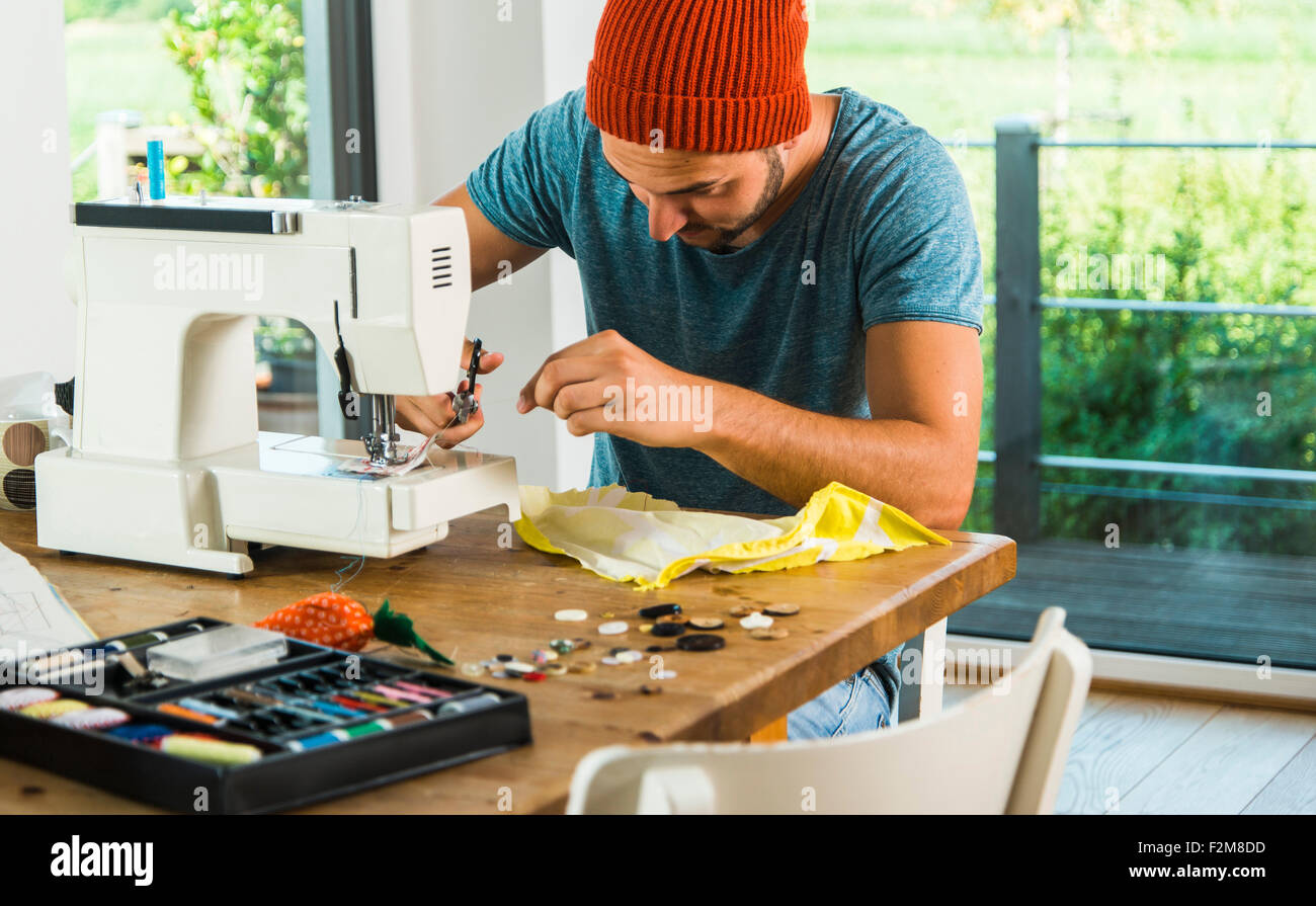 Young man at home using sewing machine Stock Photo - Alamy
