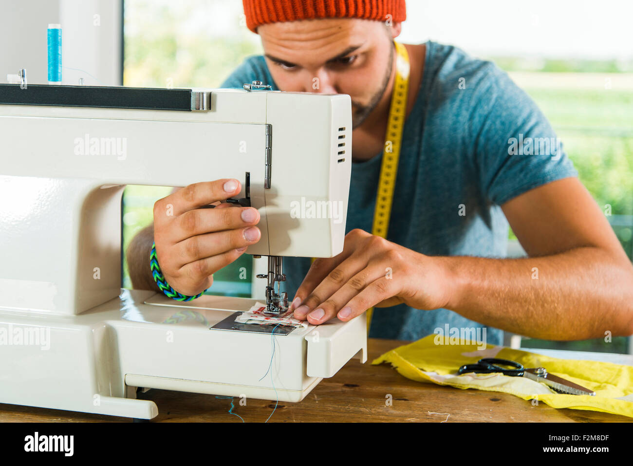 Young man at home using sewing machine Stock Photo - Alamy