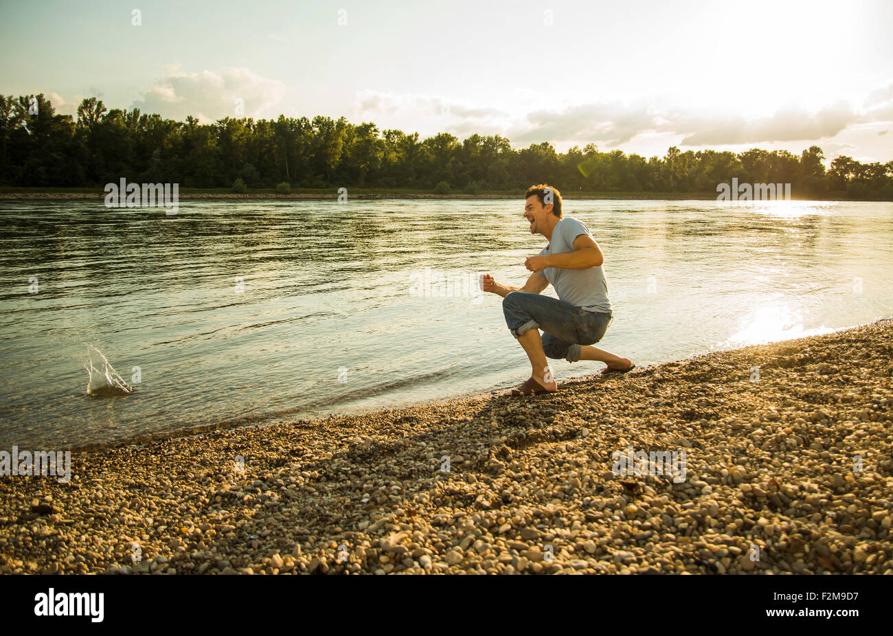Мужчина на природе. Река всплеск воды. Загрязненный берег реки. Мусор около воды. Река кинули.