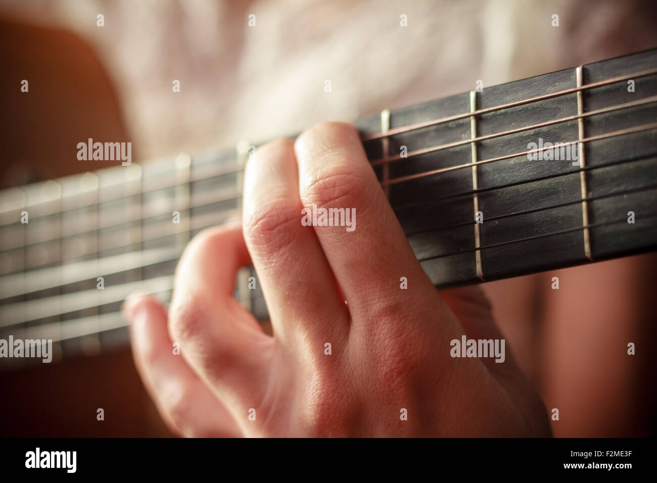 Close up on the hand of a young woman playing the guitar Stock Photo