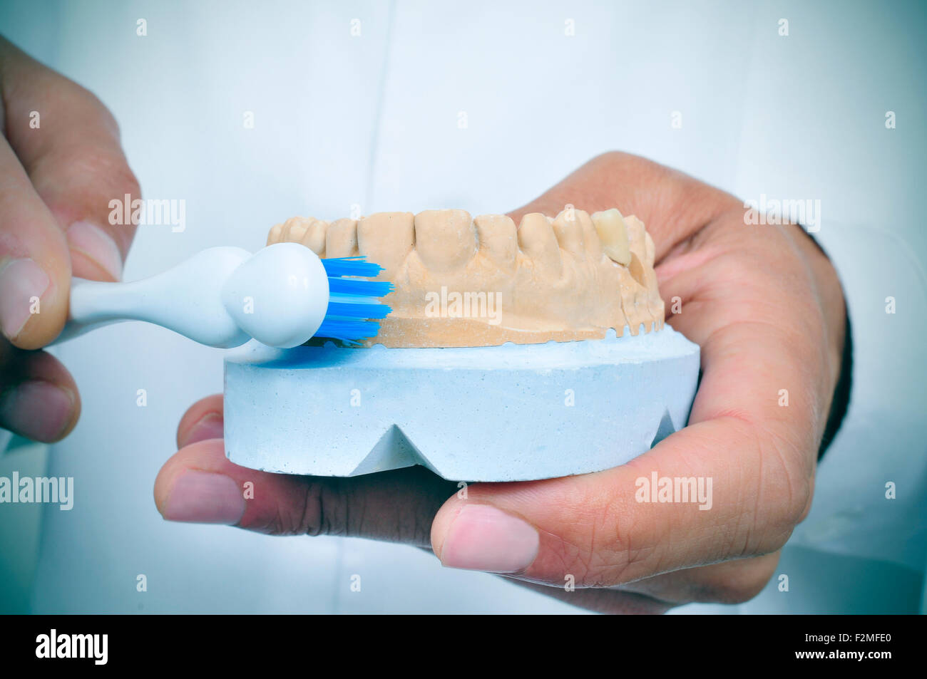 a young dentist man shows how to brush teeth with a toothbrush using a