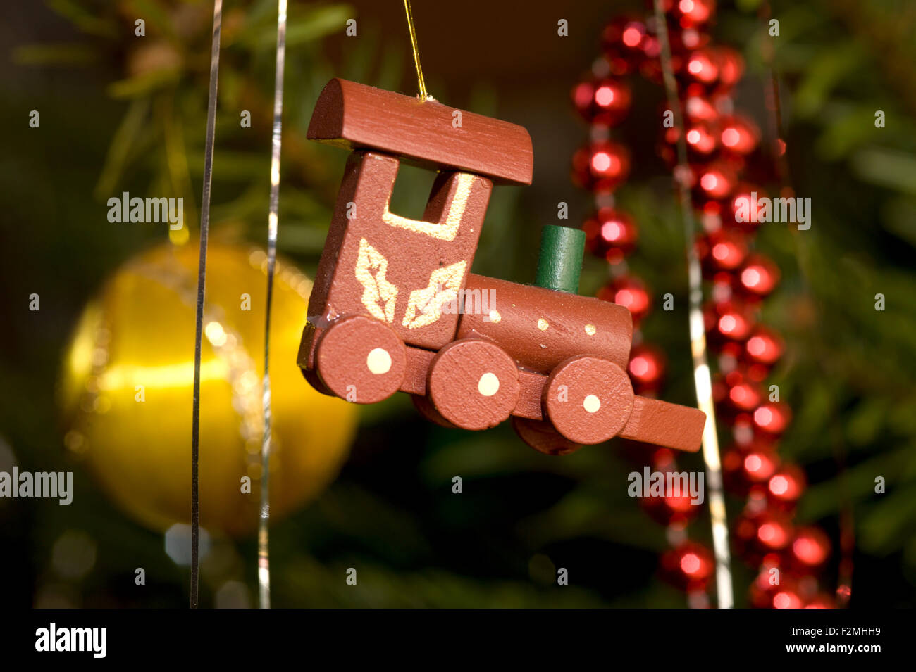 close up detail of a wooden steam engine toy hanging from a traditional christmas tree Stock Photo