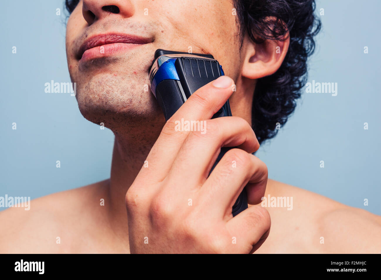Young man shaving with electrical razor Stock Photo Alamy