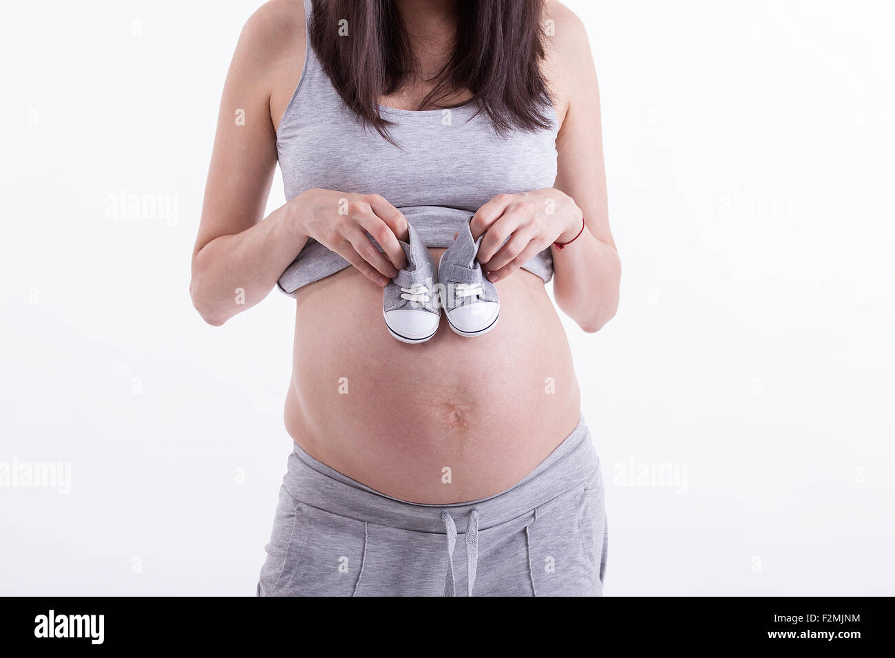 Small shoes for the unborn baby in the belly of pregnant woman Stock Photo
