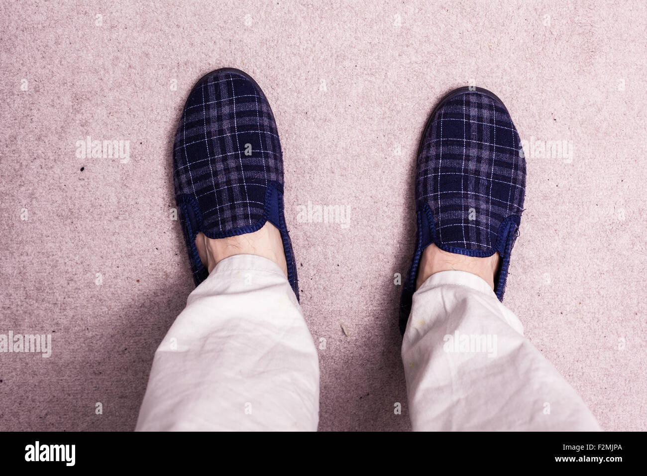Feet of man wearing slippers on carpet Stock Photo Alamy