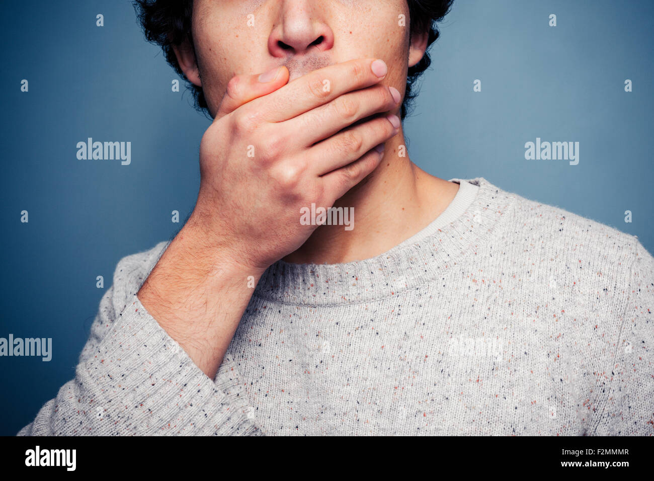 Young man covering mouth in shock Stock Photo