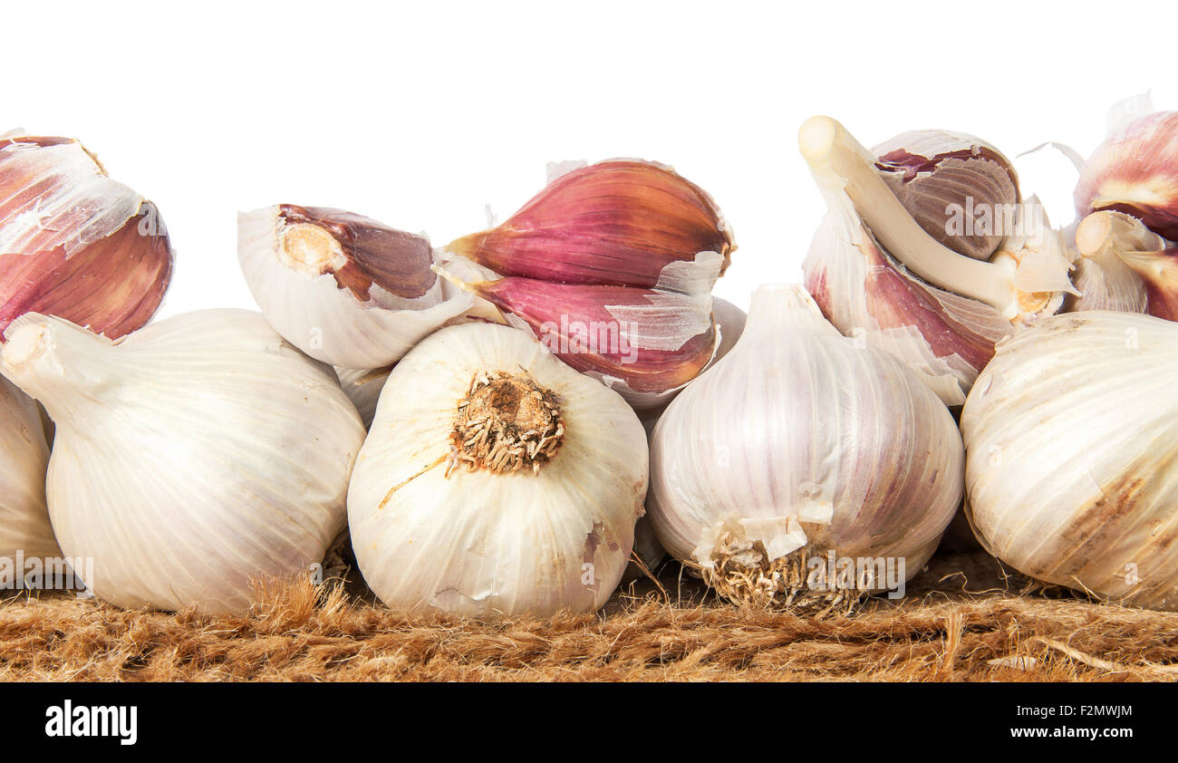 Pile of whole and cloves of garlic on sackcloth isolated on white background Stock Photo
