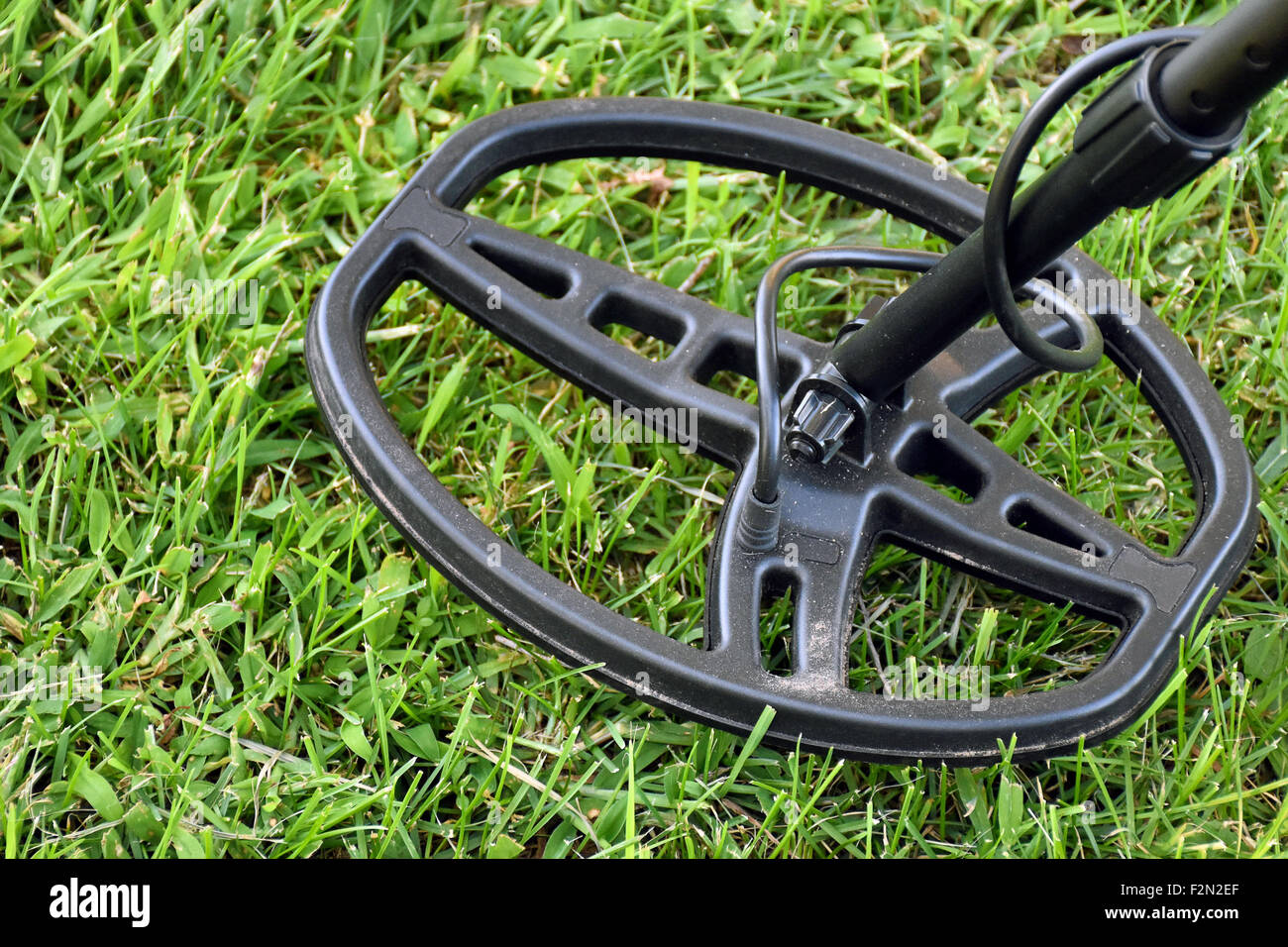 Metal detector hovering over green grass. Stock Photo