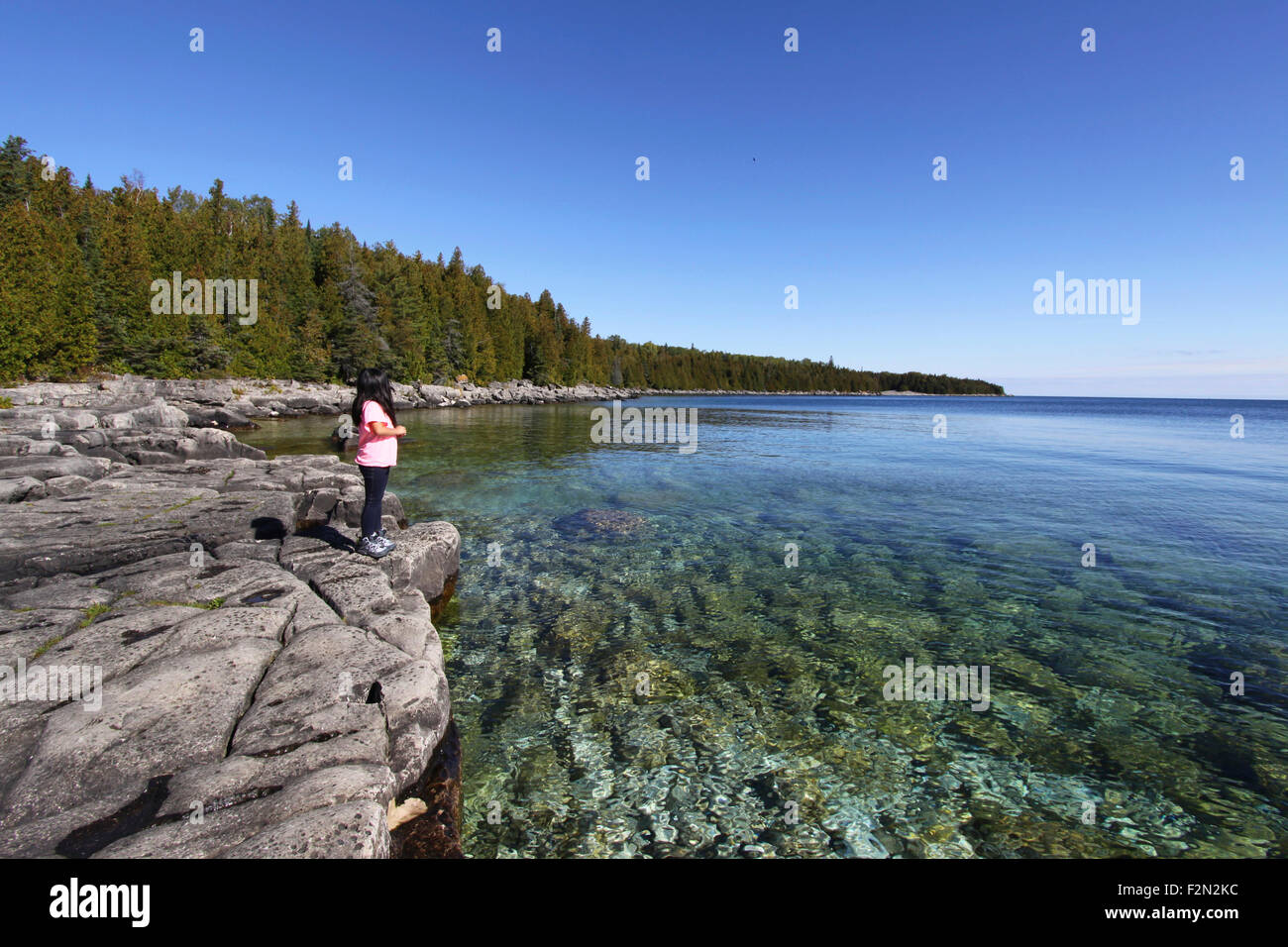 Young girl standing on rocky shore of Georgian Bay, Bruce Peninsula, Ontario, Canada. Stock Photo