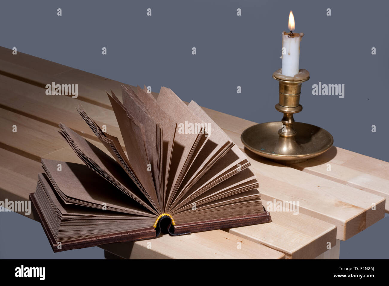 book candle candlestick wood retro old object still life bench surface brown fire flame copper bronze antique ancient symbol Stock Photo