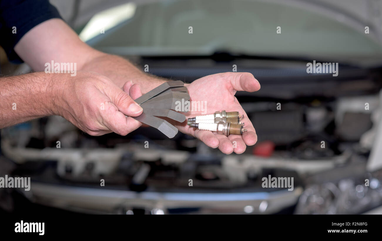 Feeler gage and spark plugs in a hand Stock Photo
