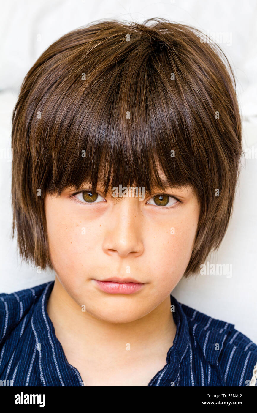 Caucasian child, boy, 10-11 year old. Brown hair, head and shoulders, facing with eye contact, staring at viewer. Annoyed, defiant    expression. Stock Photo