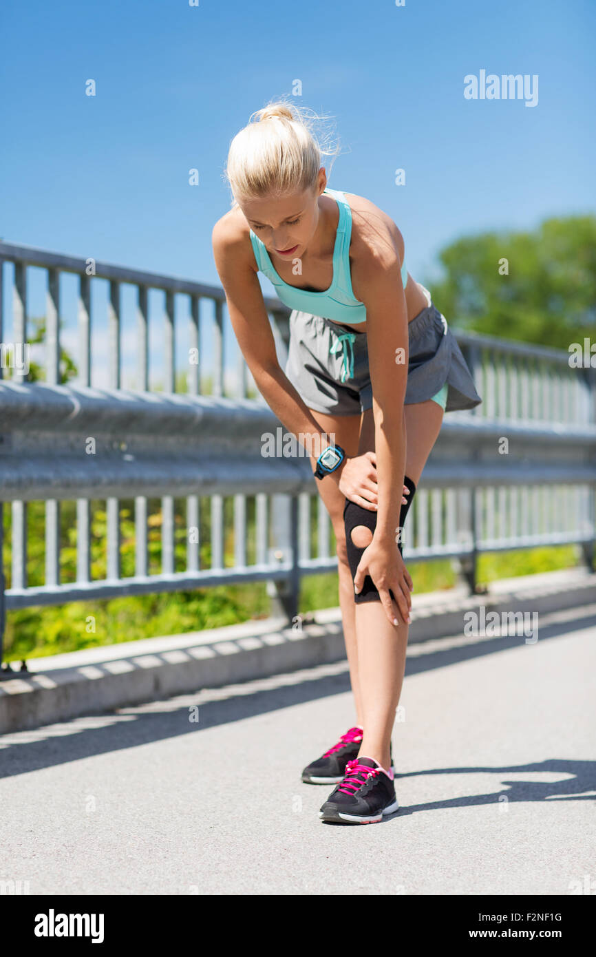young woman with injured knee or leg outdoors Stock Photo