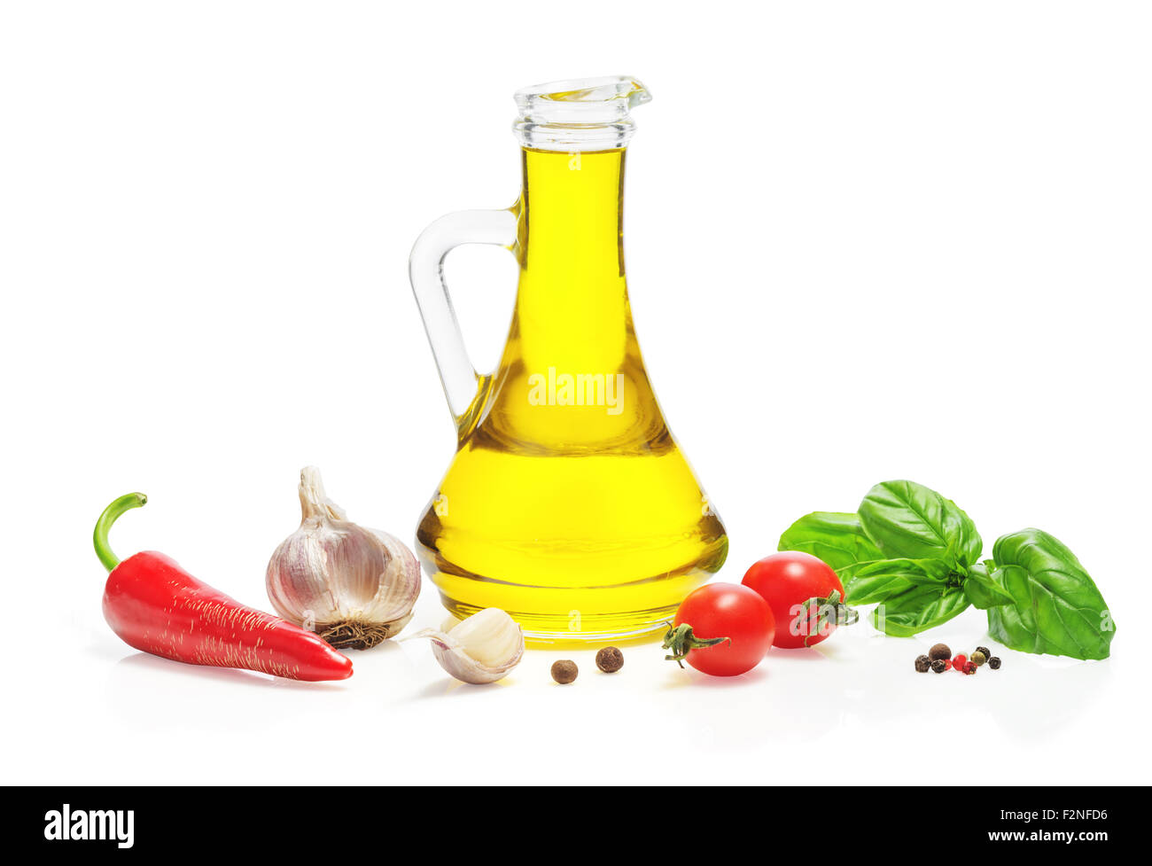 Olive oil in a glass jug, red hot chili peppers, cherry tomatoes, allspice, a mixture of peppers, basil, garlic isolated Stock Photo