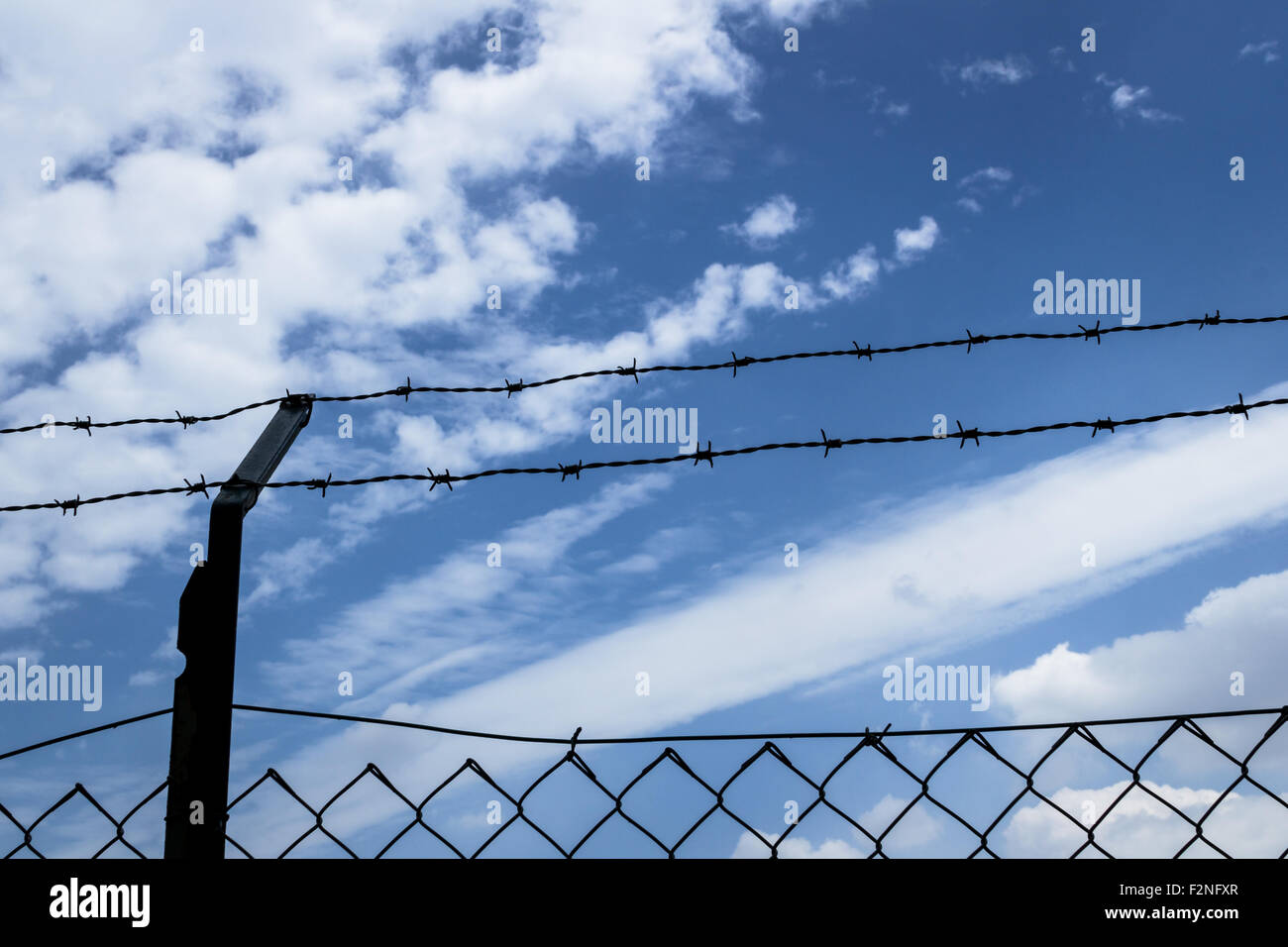 Barbed wire fence with blue sky and clouds in the background Stock ...