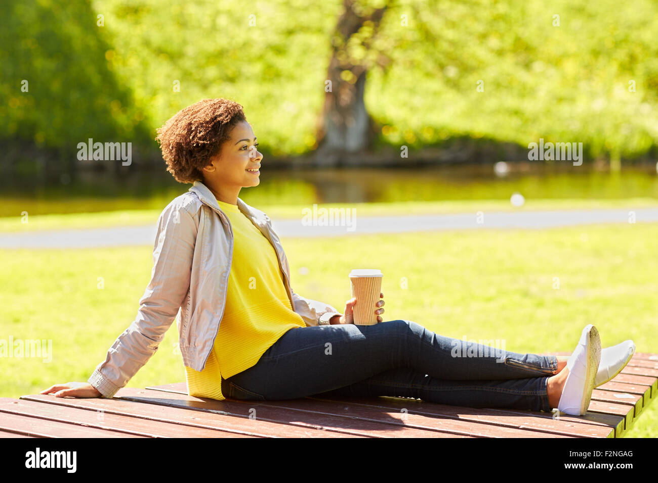 happy african woman drinks coffee at summer park Stock Photo - Alamy