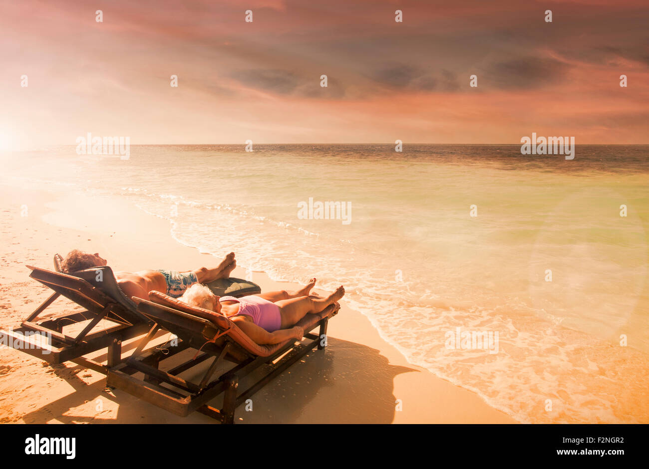 Older Caucasian couple relaxing on beach at sunset Stock Photo - Alamy