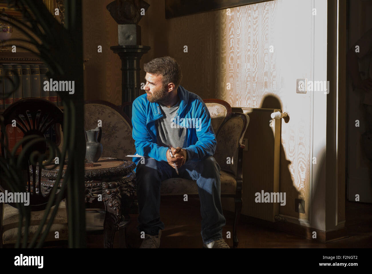 Caucasian man sitting in sunlight in living room Stock Photo