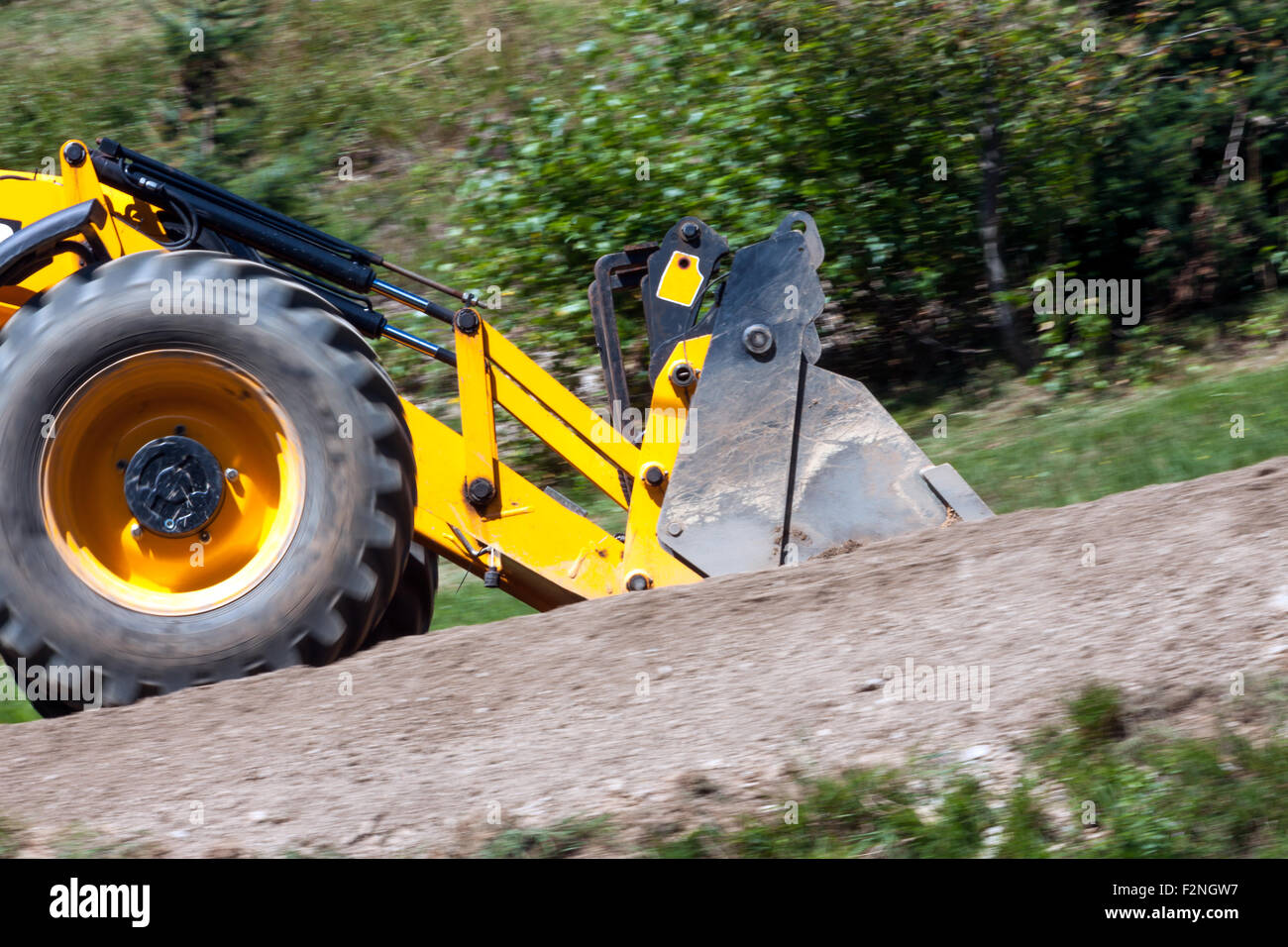 detail yellow excavator traveling on the road, panning image Stock Photo
