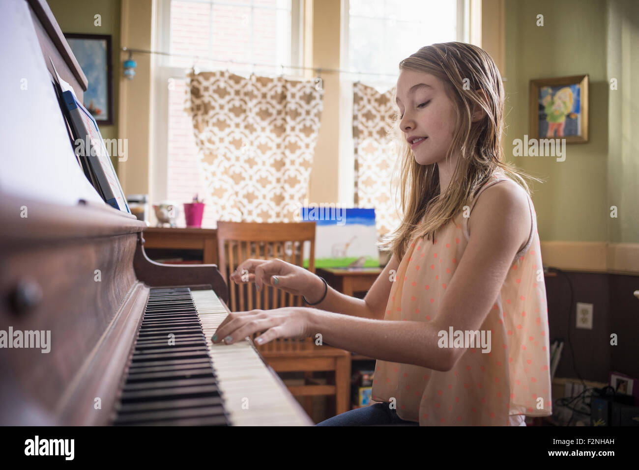 Caucasian girl playing piano in living room Stock Photo