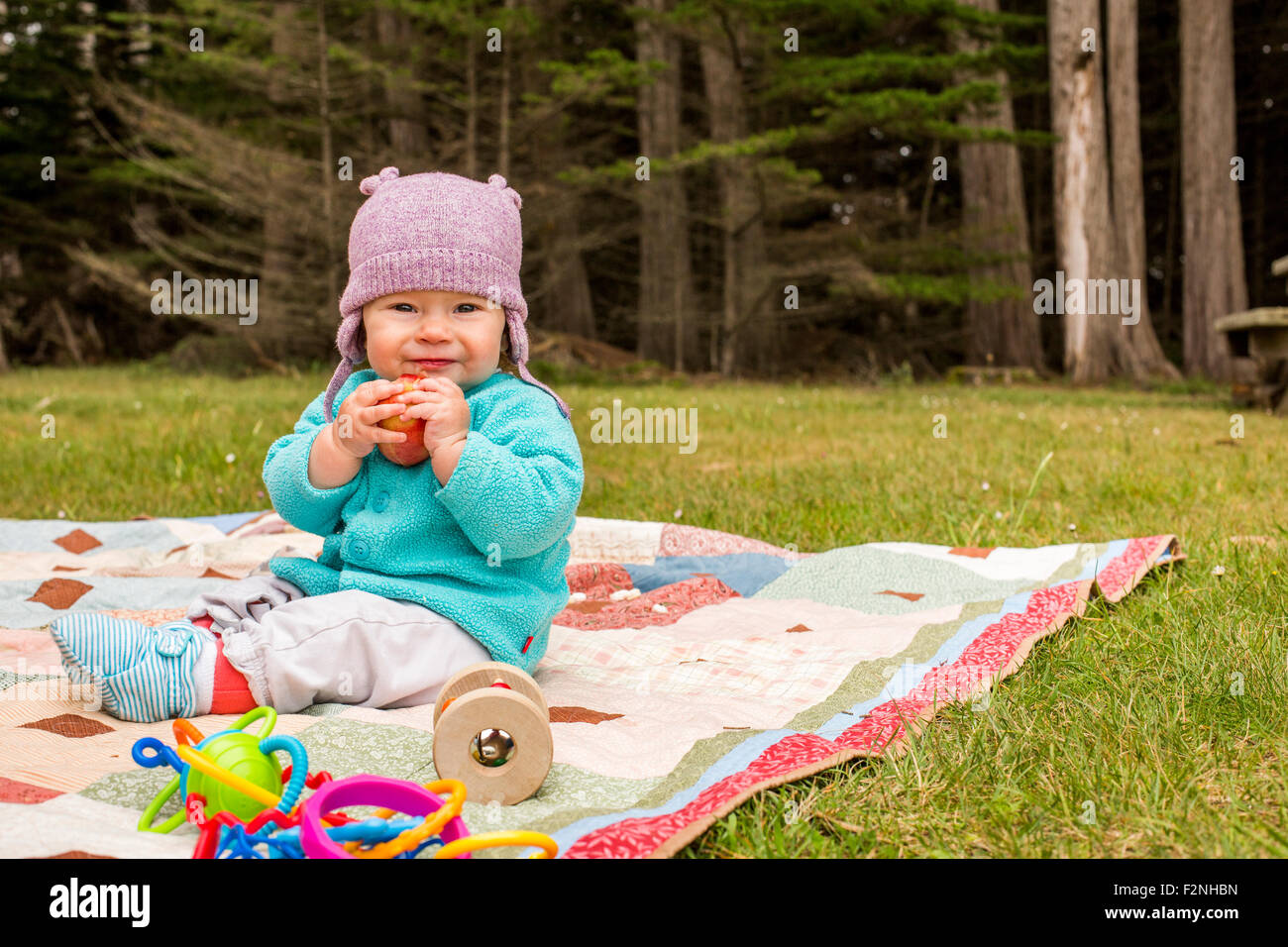 Caucasian baby girl sitting on blanket in grass Stock Photo