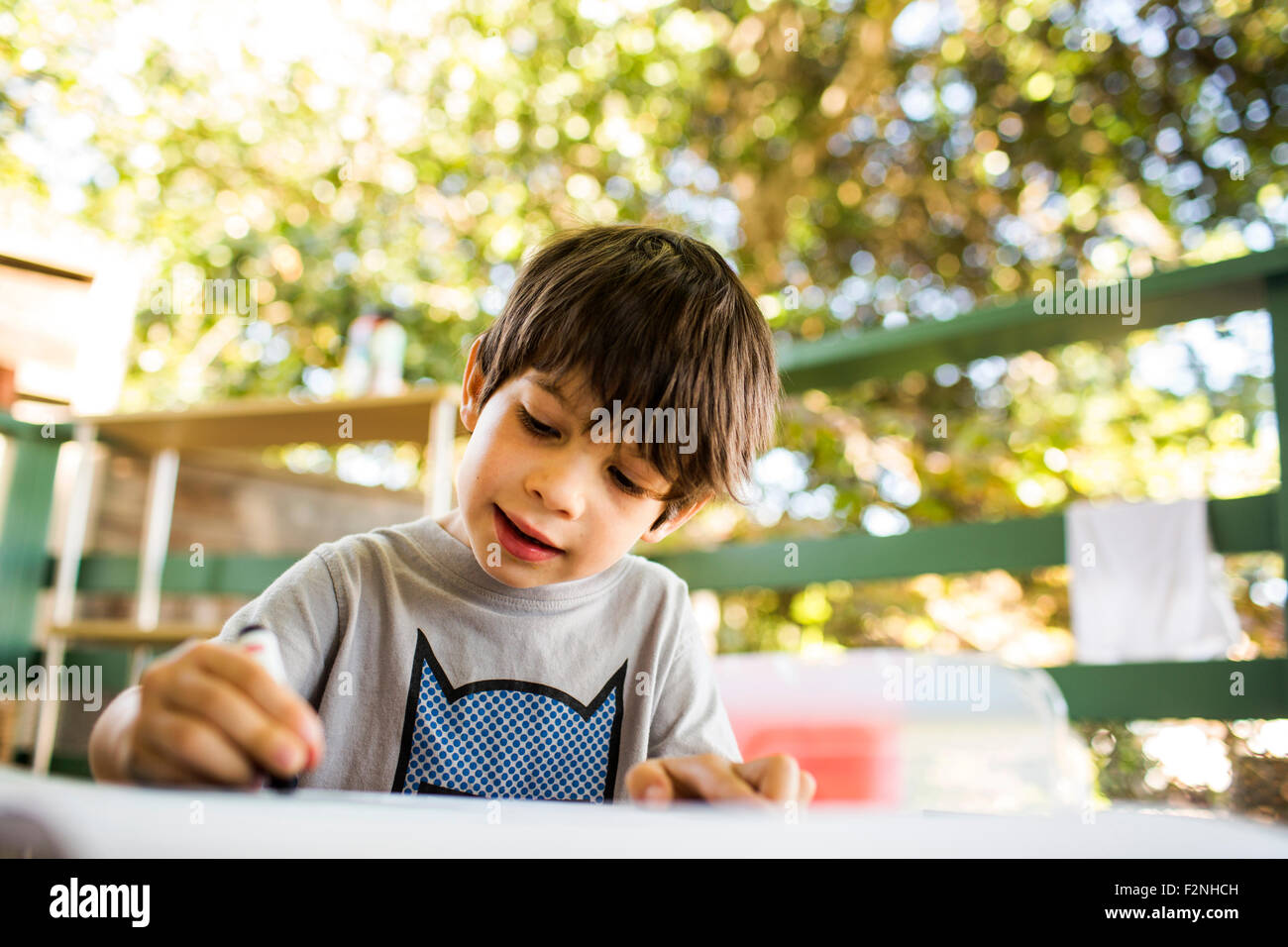 Mixed race boy coloring on porch Stock Photo