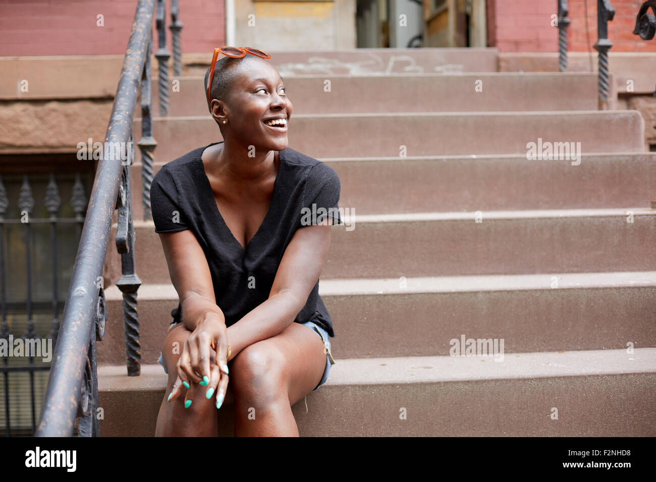 Black woman sitting on urban front stoop Stock Photo