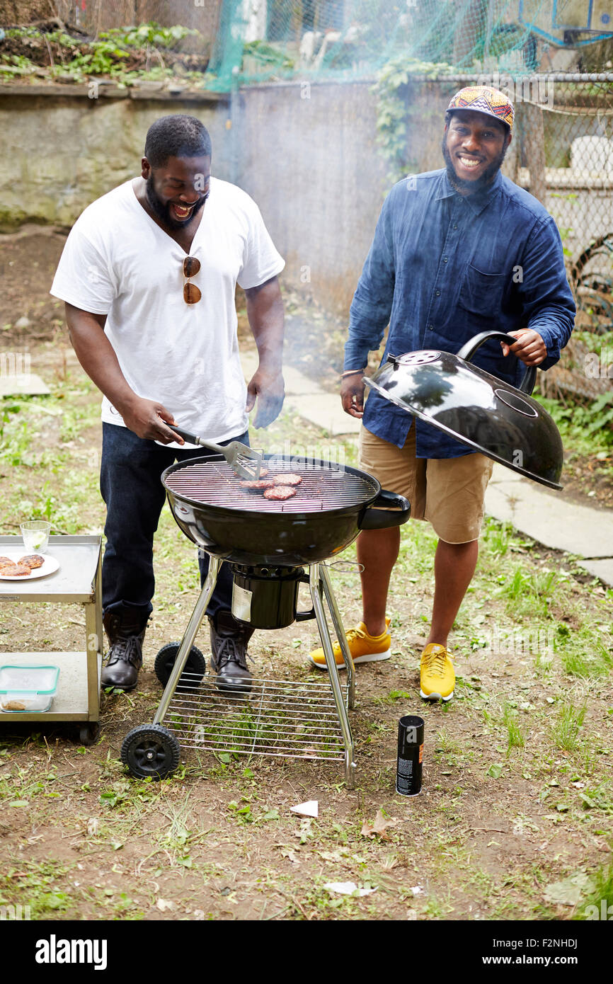 Black men grilling hamburgers at backyard barbecue Stock Photo