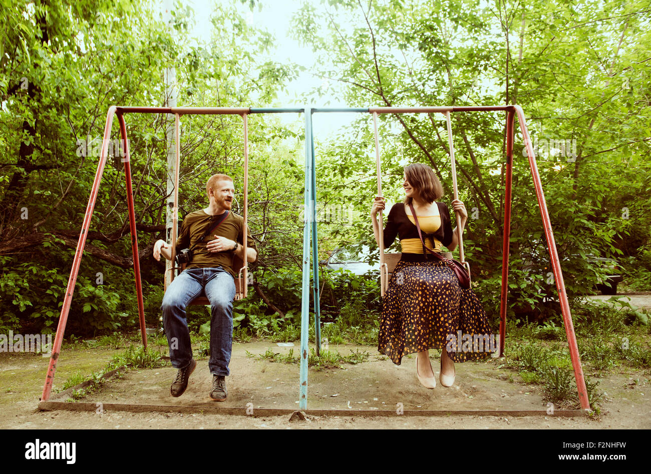 Caucasian couple playing on swing set Stock Photo