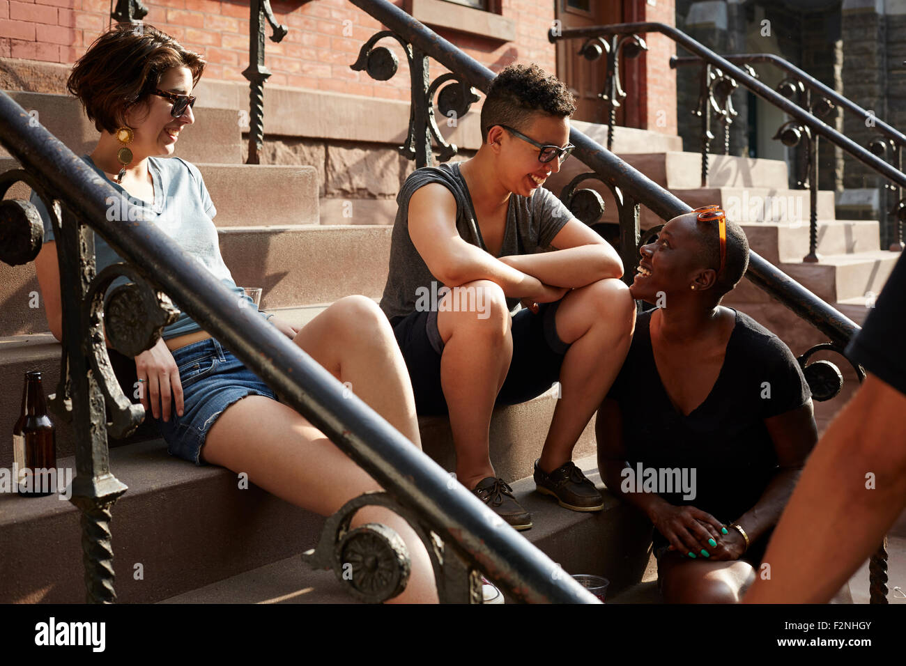 Friends relaxing on front stoop Stock Photo