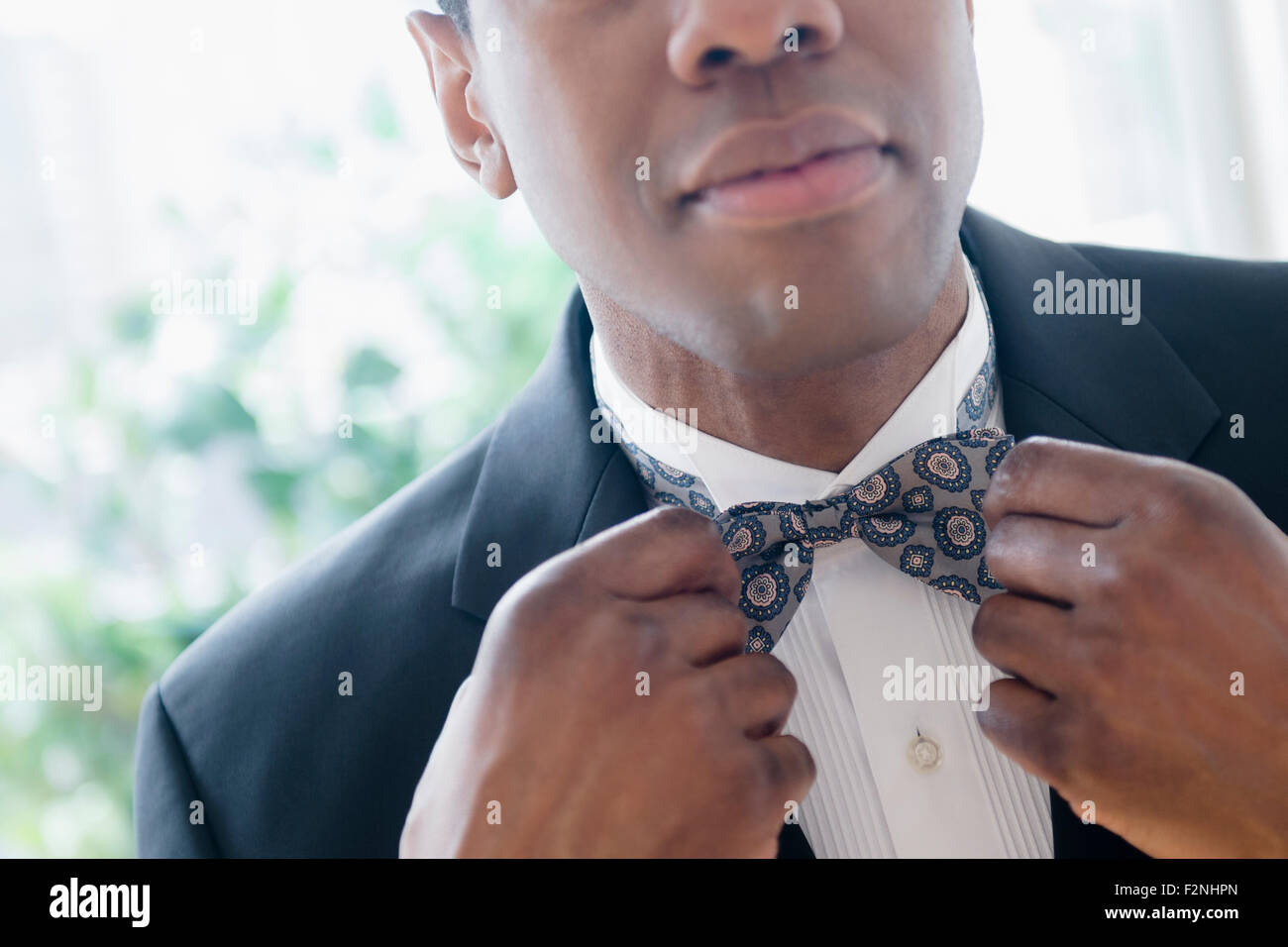 Groom in tuxedo adjusting bow tie Stock Photo